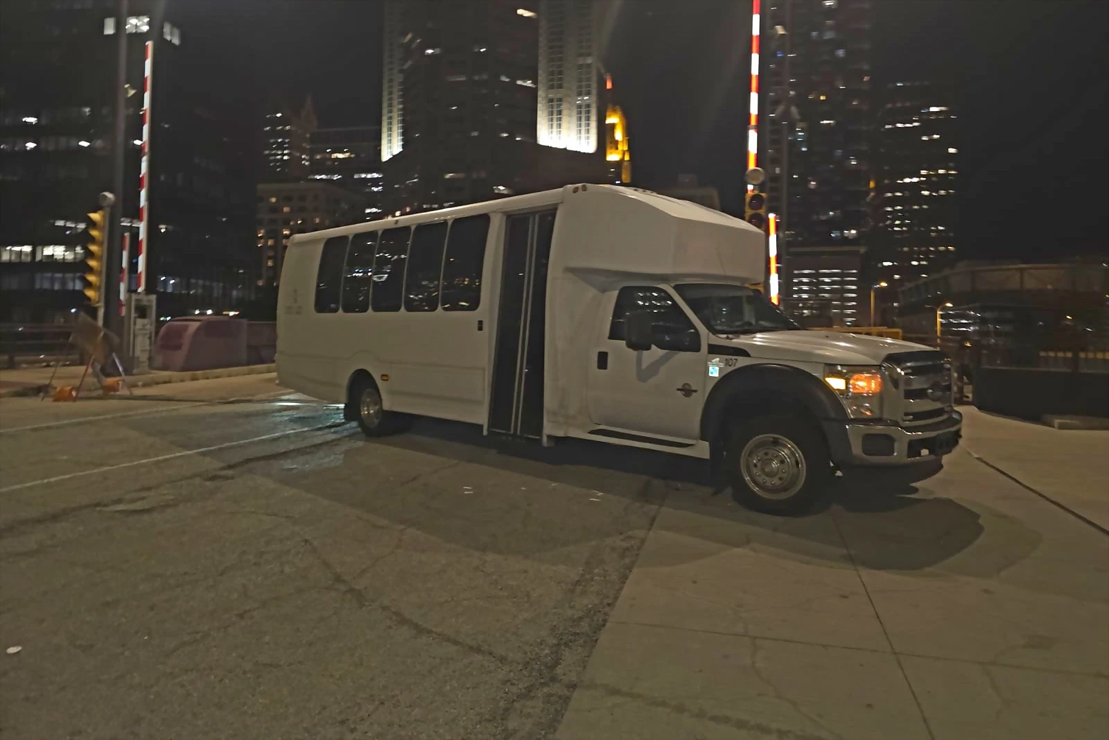 White shuttle mini bus at night with the Chicago skyline behind