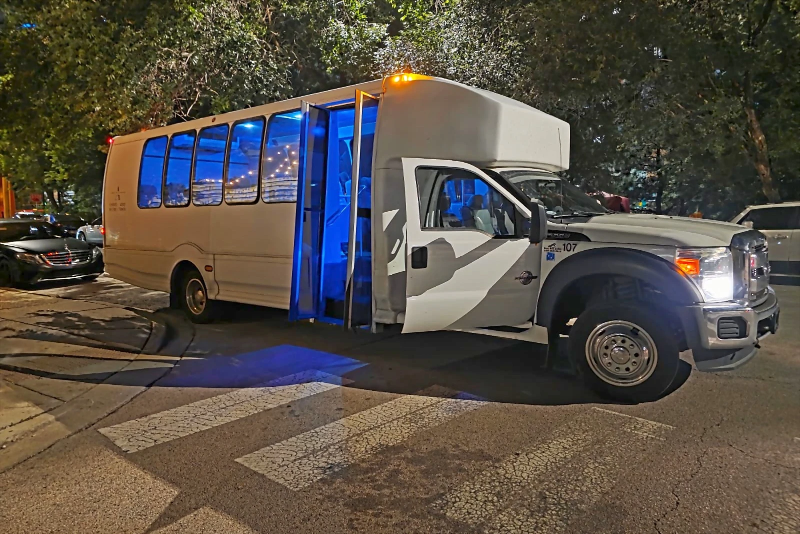 White mini bus with its blue-lit door open at night