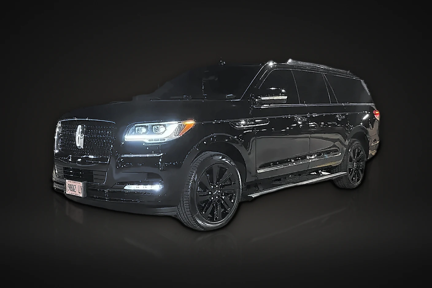 Black Lincoln Navigator L with its headlights on