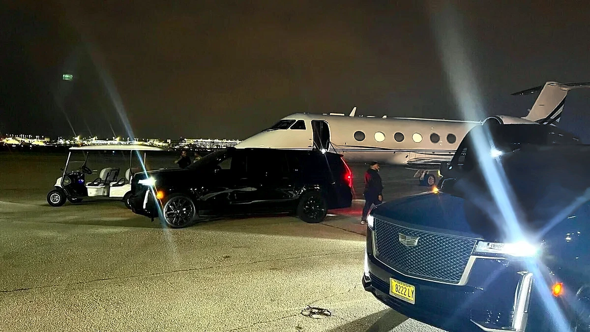 Black Cadillac Escalades beside a private jet at night